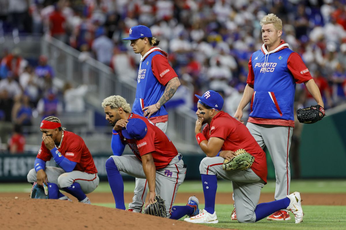 Puerto Rico players take a knee as pitcher Edwin Diaz (not pictured) gets checked on by training staff after an apparent leg injury during the team celebration against Dominican Republic at LoanDepot Park.
